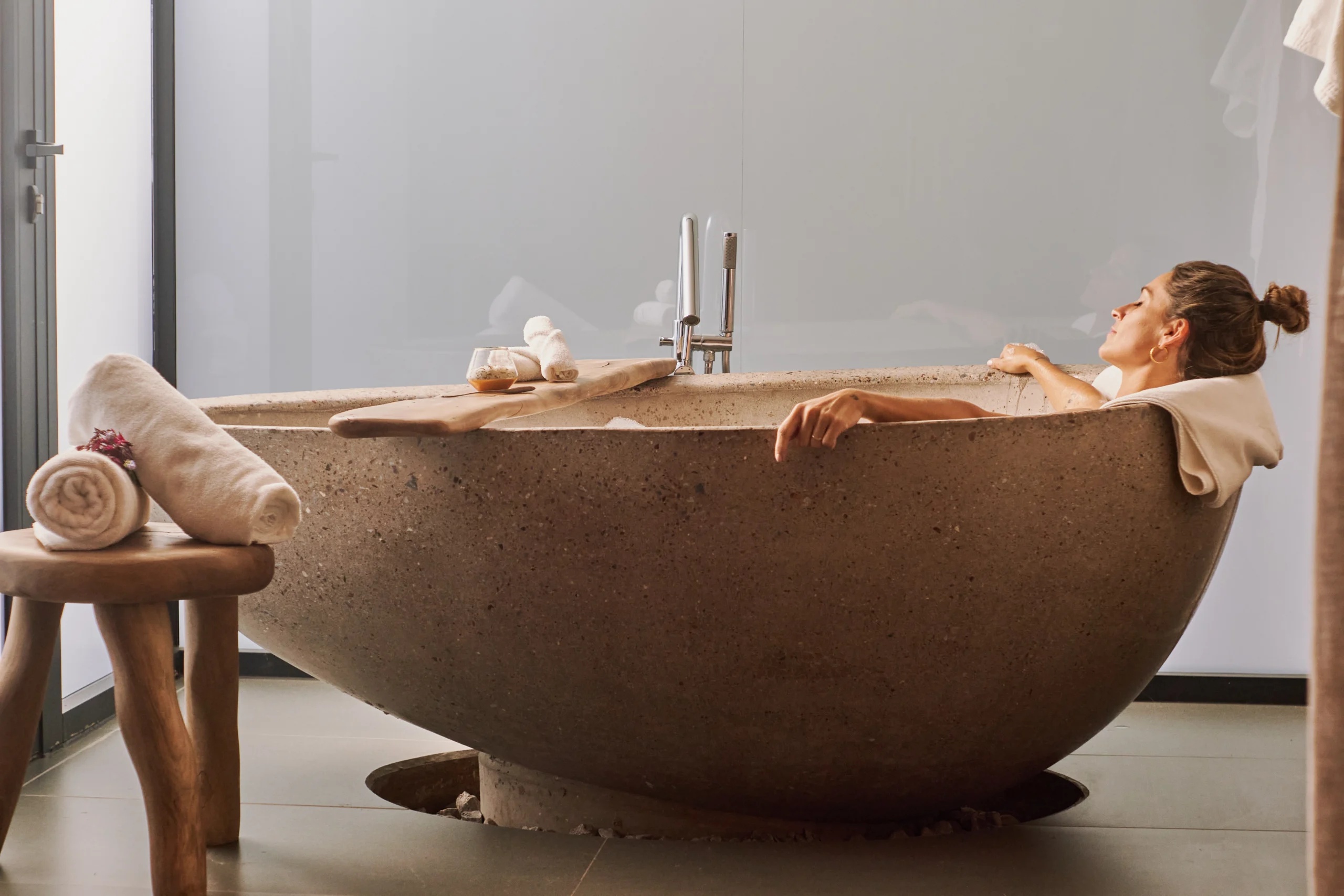 Guest relaxing in a concrete soaking tub made from repurposed winery fermentation vessels, Susana Balbo Winemaker's House